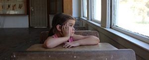Child sitting at a school desk and gazing out of the window