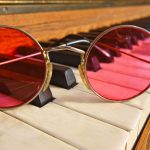 Spectacles with red lenses on a piano