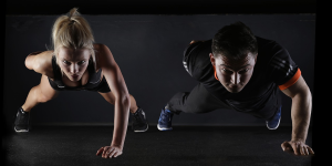 Photo of a man and a woman doing one-handed pushups.