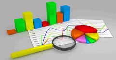 A bar chart built from blocks, on top of a paper with a graph chart, and a pie chart.